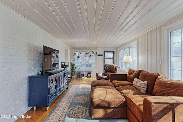 living area featuring brick wall, wood finished floors, and a wood stove