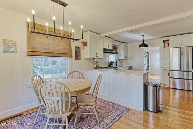 kitchen featuring a peninsula, white cabinetry, light countertops, and freestanding refrigerator