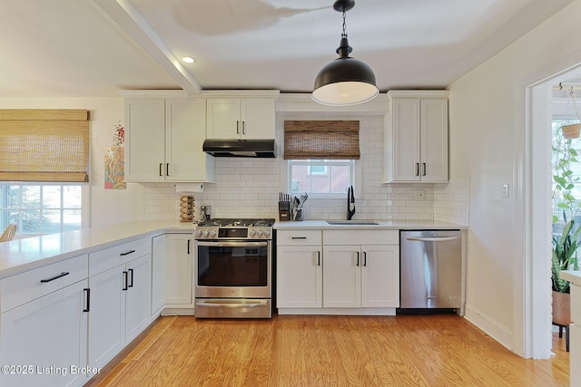 kitchen featuring light countertops, appliances with stainless steel finishes, a sink, and under cabinet range hood