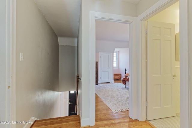 hall with an upstairs landing and light wood-style flooring