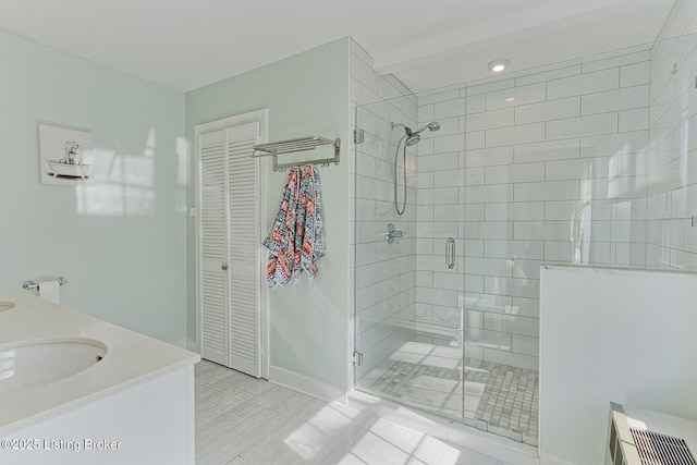 bathroom with baseboards, a closet, vanity, and a stall shower