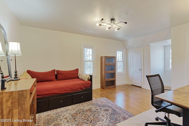 bedroom featuring vaulted ceiling, light wood-style flooring, and baseboards