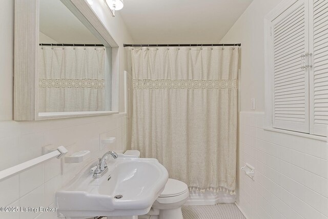 bathroom featuring tile walls, toilet, shower / tub combo, a sink, and tile patterned floors