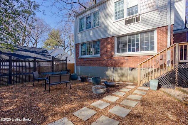 back of house with stairway, fence, and brick siding