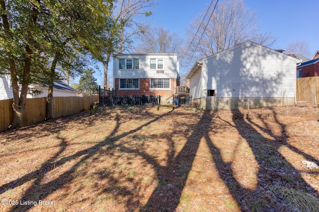 rear view of property featuring brick siding and a fenced backyard