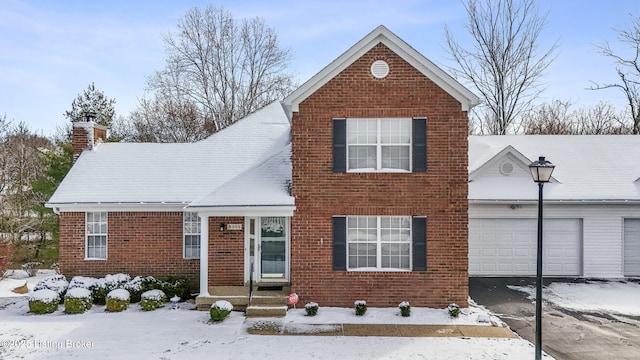 traditional-style home featuring brick siding, an attached garage, and driveway