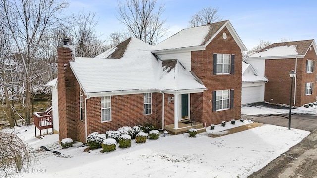 traditional-style house with brick siding, a chimney, a garage, and an outdoor structure