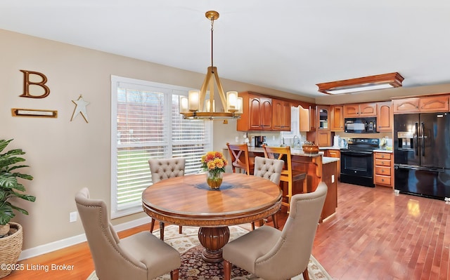 dining space with light wood-style flooring, baseboards, and an inviting chandelier