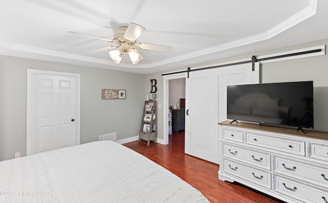 bedroom featuring a barn door, visible vents, a ceiling fan, ornamental molding, and dark wood finished floors