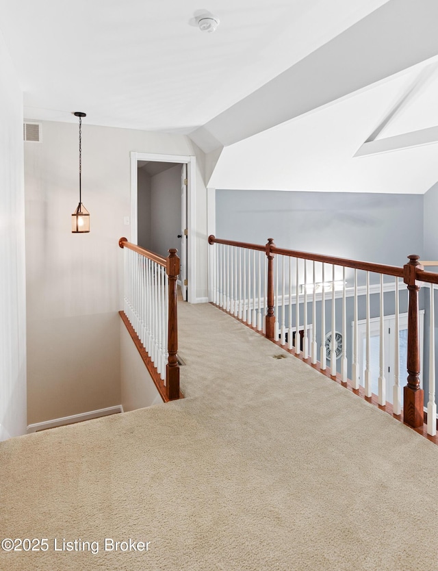 corridor with lofted ceiling with skylight, visible vents, an upstairs landing, and carpet flooring