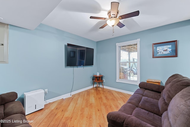 living room featuring light wood-style floors, baseboards, and a ceiling fan