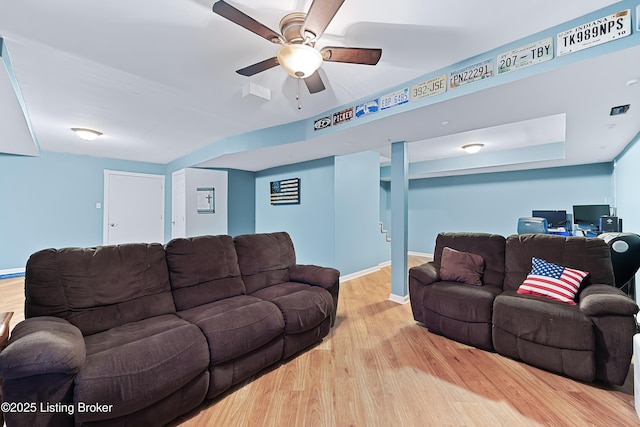 living area featuring a ceiling fan, baseboards, and wood finished floors