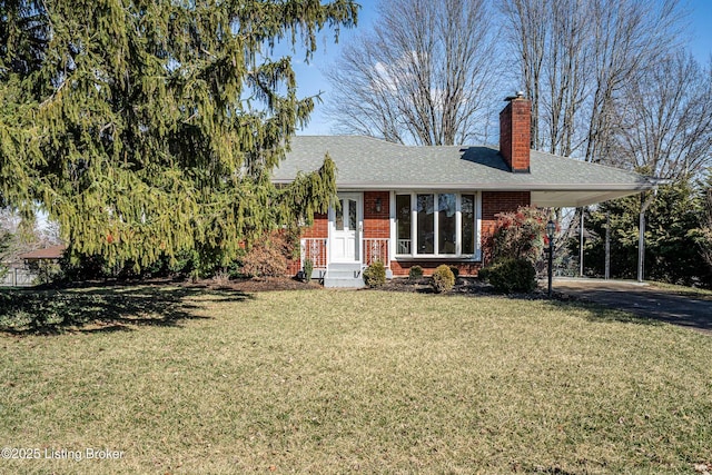 view of front of house featuring a front yard, a chimney, a carport, and brick siding