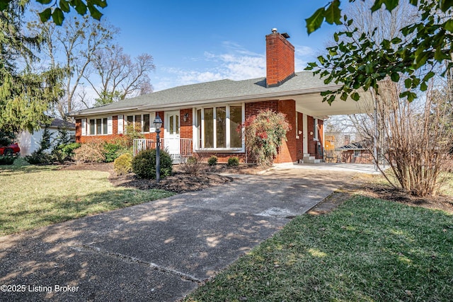 single story home featuring brick siding, a chimney, a carport, driveway, and a front lawn