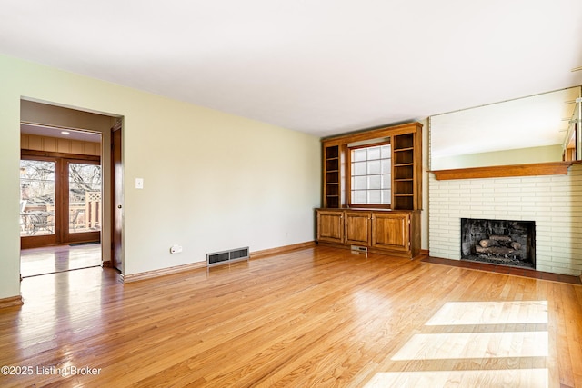 unfurnished living room featuring light wood-type flooring, baseboards, a fireplace, and visible vents