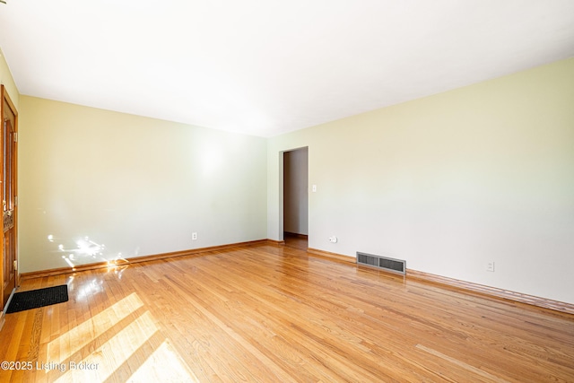 unfurnished room featuring light wood-style flooring, visible vents, and baseboards