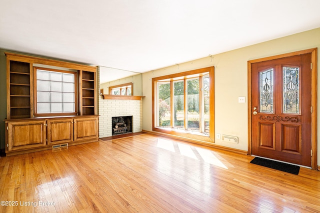 unfurnished living room featuring visible vents, a fireplace, light wood-style flooring, and baseboards