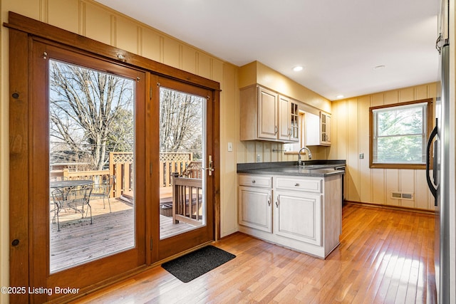 kitchen featuring dark countertops, visible vents, glass insert cabinets, freestanding refrigerator, and light wood-type flooring