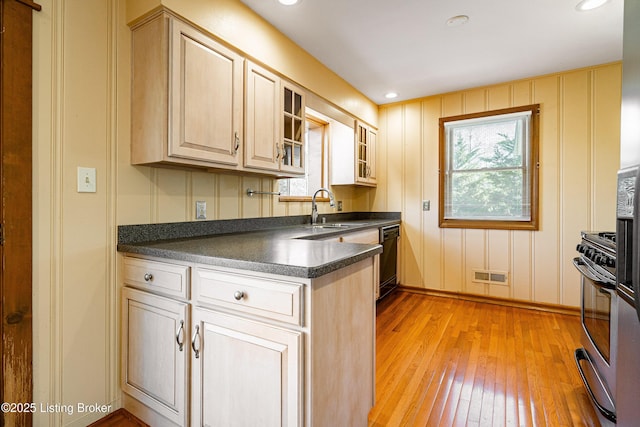 kitchen with visible vents, dark countertops, light wood-style flooring, glass insert cabinets, and a sink