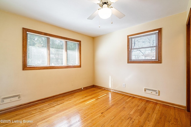 spare room with a ceiling fan, light wood-style flooring, visible vents, and baseboards