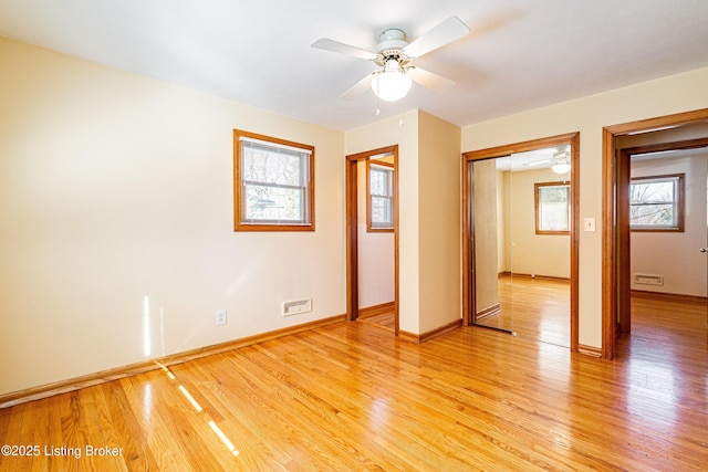 interior space featuring baseboards, multiple windows, and light wood finished floors