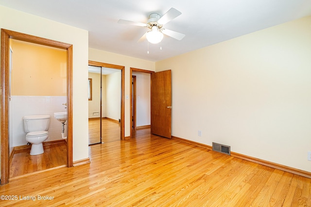 unfurnished bedroom featuring a closet, tile walls, visible vents, and light wood-style floors