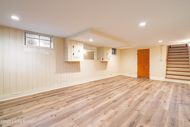 below grade area with baseboards, stairway, light wood-style flooring, and recessed lighting