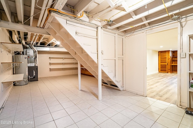 unfinished below grade area featuring water heater and light tile patterned flooring