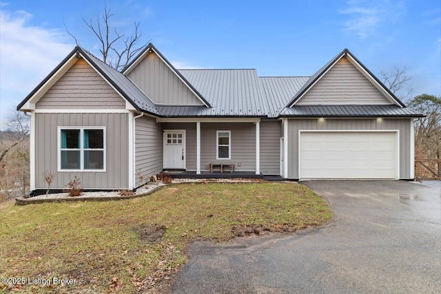 view of front of house featuring a garage, metal roof, aphalt driveway, a front lawn, and board and batten siding