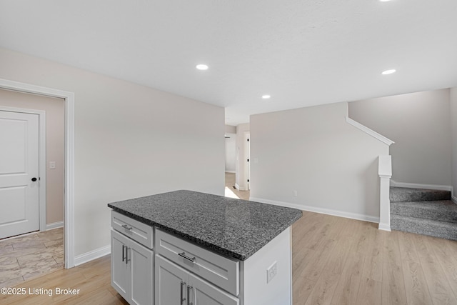 kitchen featuring a center island, open floor plan, light wood-style flooring, and baseboards