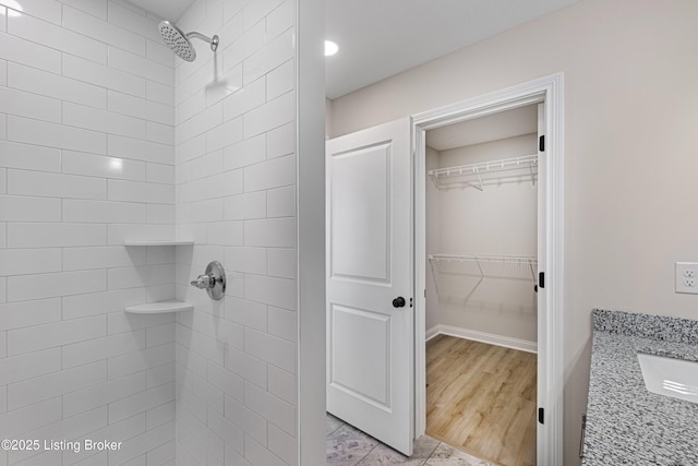 bathroom with a tile shower and vanity