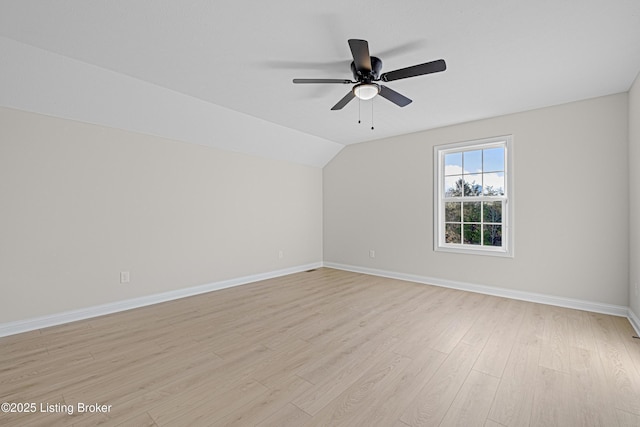 interior space with a ceiling fan, lofted ceiling, baseboards, and light wood finished floors