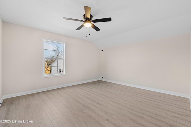 spare room featuring vaulted ceiling, ceiling fan, light wood-type flooring, and baseboards