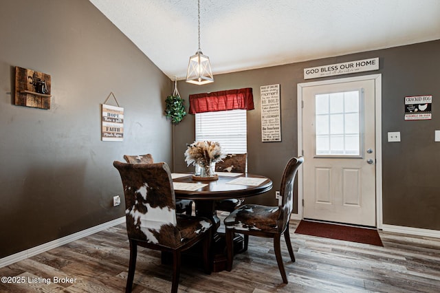 dining area featuring lofted ceiling, baseboards, and wood finished floors