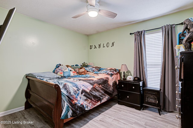 bedroom with baseboards, light wood-style flooring, and a ceiling fan