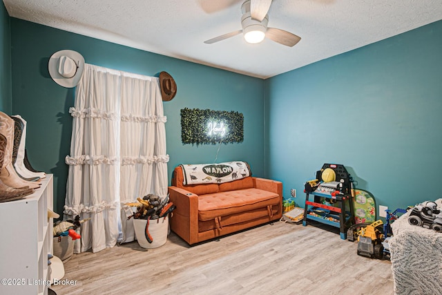 bedroom featuring a ceiling fan, light wood-type flooring, and a textured ceiling