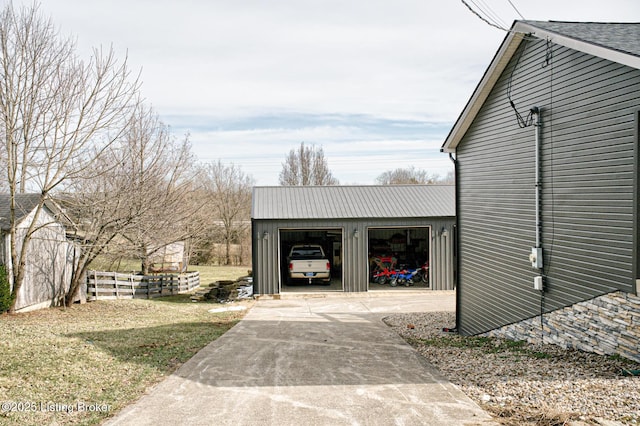 view of outbuilding with a garage, an outdoor structure, driveway, and fence