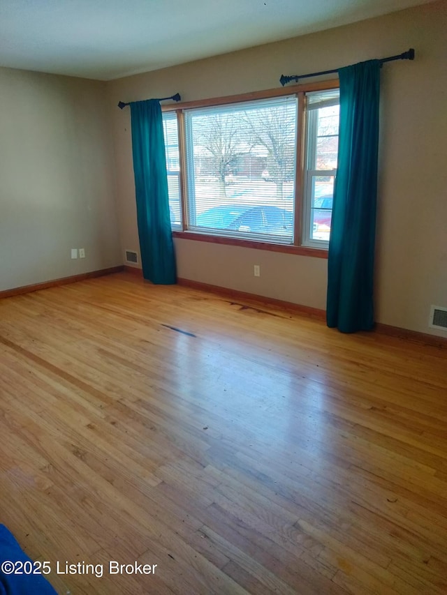 unfurnished room with light wood-style flooring, plenty of natural light, and visible vents