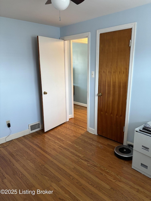 unfurnished bedroom featuring wood finished floors, visible vents, and baseboards