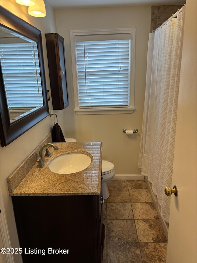 bathroom with toilet, baseboards, and vanity