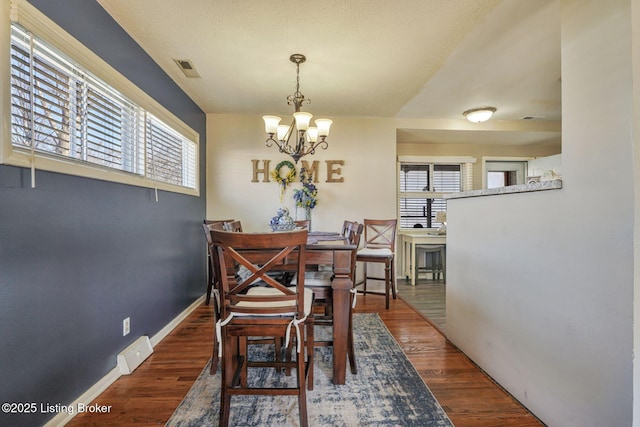 dining area featuring baseboards, visible vents, an inviting chandelier, and wood finished floors