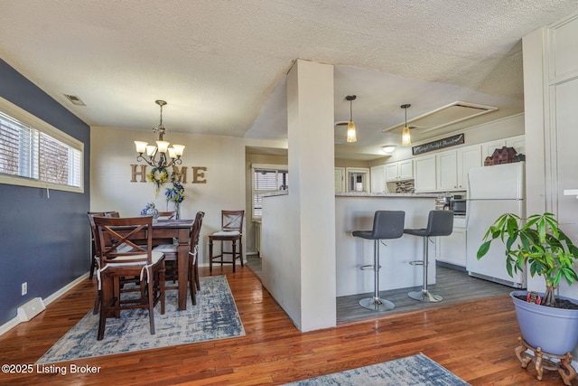 dining room with dark wood-type flooring, visible vents, and a textured ceiling