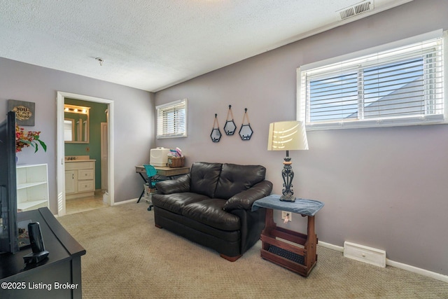 living room with a wealth of natural light, a textured ceiling, visible vents, and carpet flooring