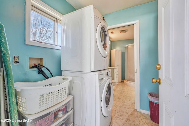 washroom with stacked washer and dryer, laundry area, baseboards, and light floors