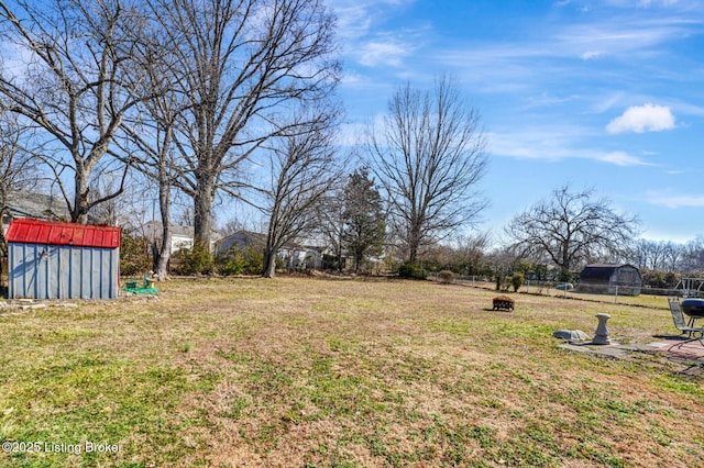 view of yard featuring an outbuilding, a storage shed, and fence