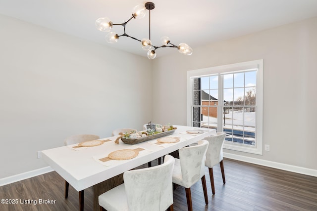 dining space featuring dark wood-style floors, baseboards, and a notable chandelier