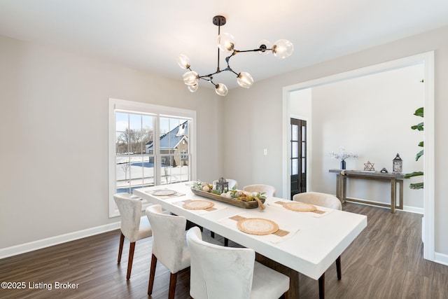 dining space featuring a chandelier, dark wood finished floors, and baseboards