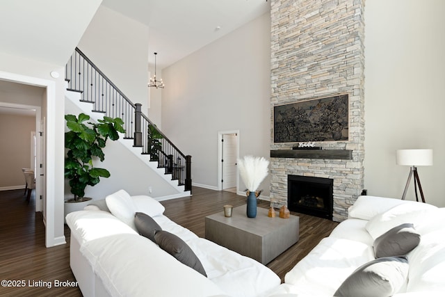 living room featuring a fireplace, dark wood finished floors, baseboards, and stairs