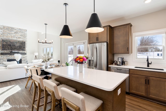 kitchen with decorative backsplash, appliances with stainless steel finishes, light countertops, pendant lighting, and a sink