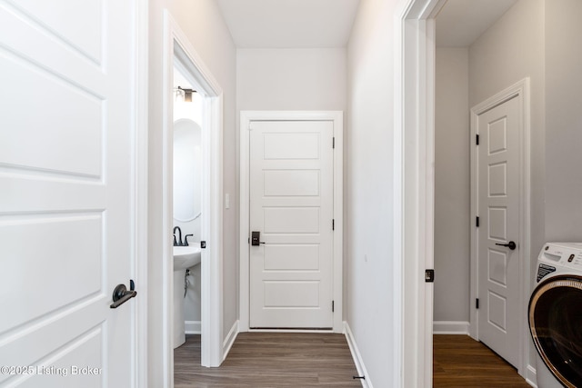 clothes washing area with washer / clothes dryer, baseboards, dark wood-style flooring, and laundry area